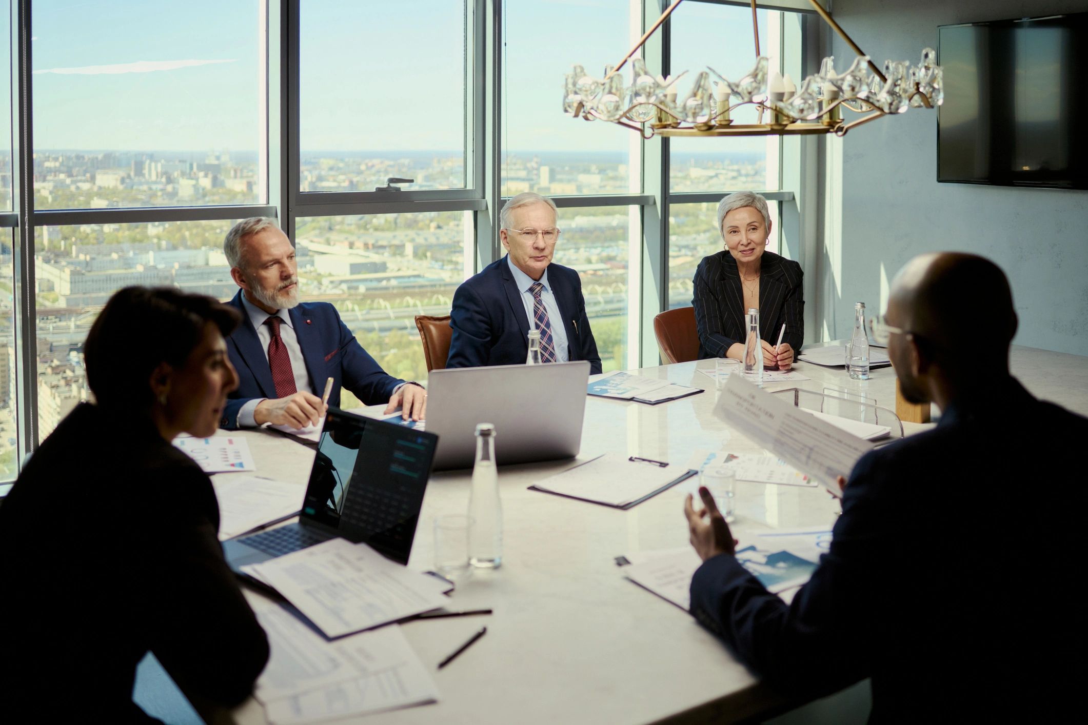Business team meeting around reports and laptops